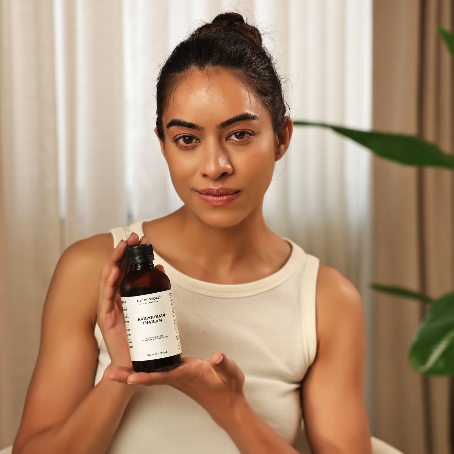 Art of Vedas Karpooradi Thailam - Woman Holding Ayurvedic Camphor Oil for Pain Relief and Warming Therapy